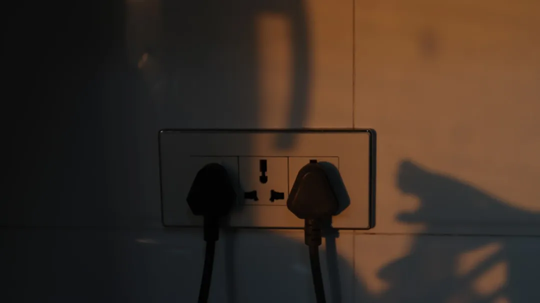Enchufe de pared con dos clavijas conectadas, iluminación cálida de atardecer