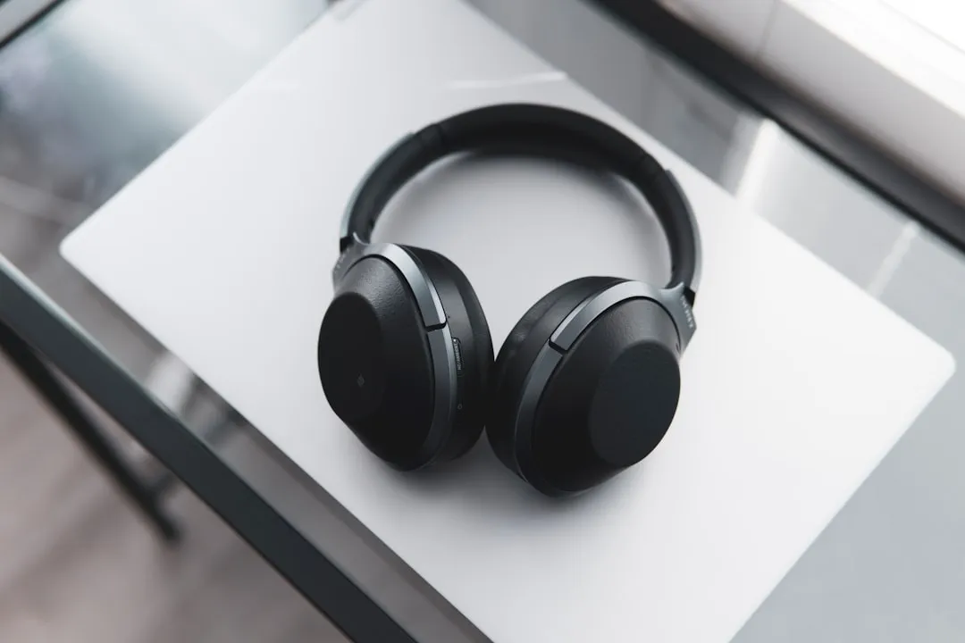 Auriculares inalámbricos con diadema sobre una mesa de cristal, en un espacio de trabajo